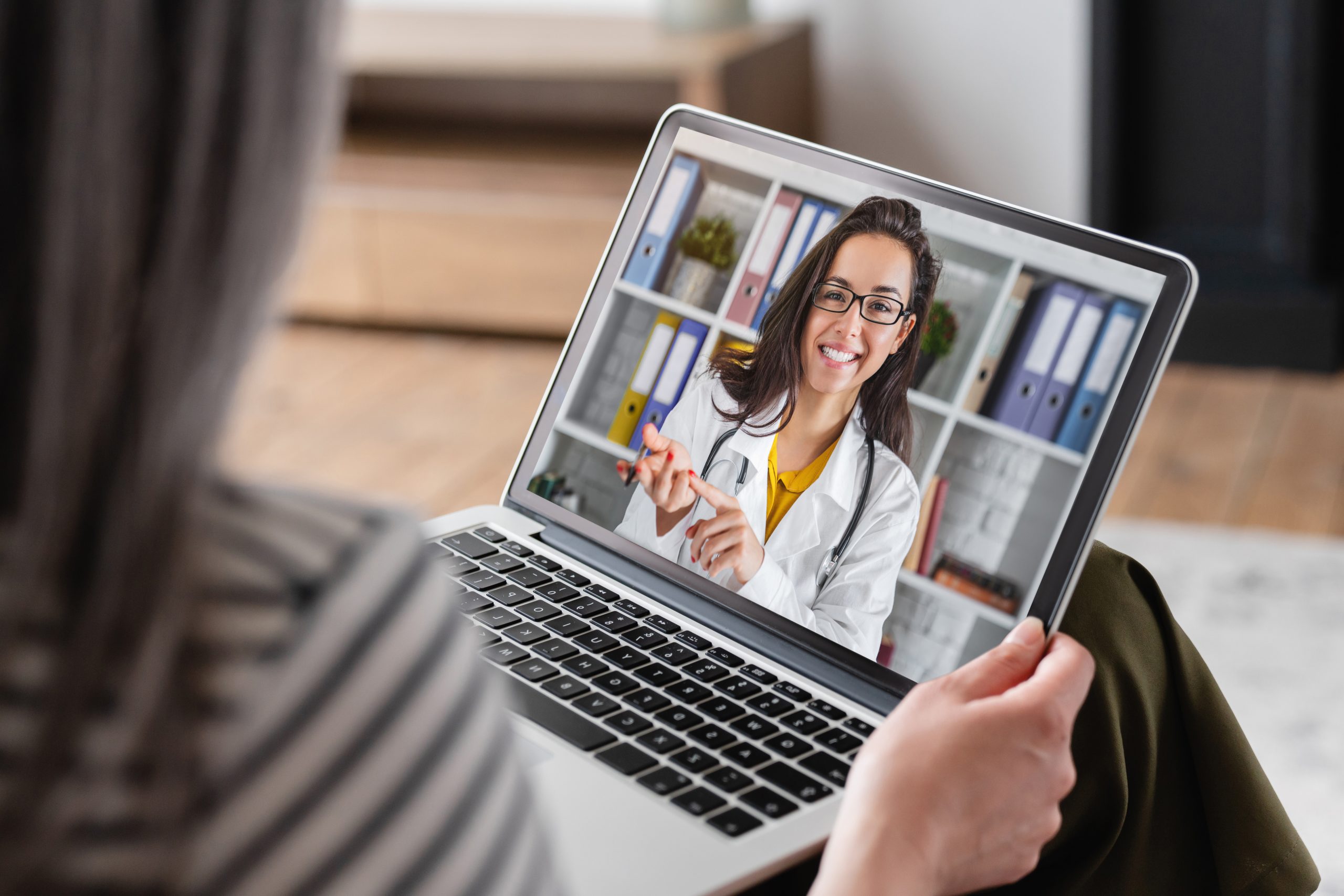 Woman using her laptop computer to have a telehealth meeting with her doctor. Elderly woman using her laptop computer to have a telehealth meeting with her doctor.